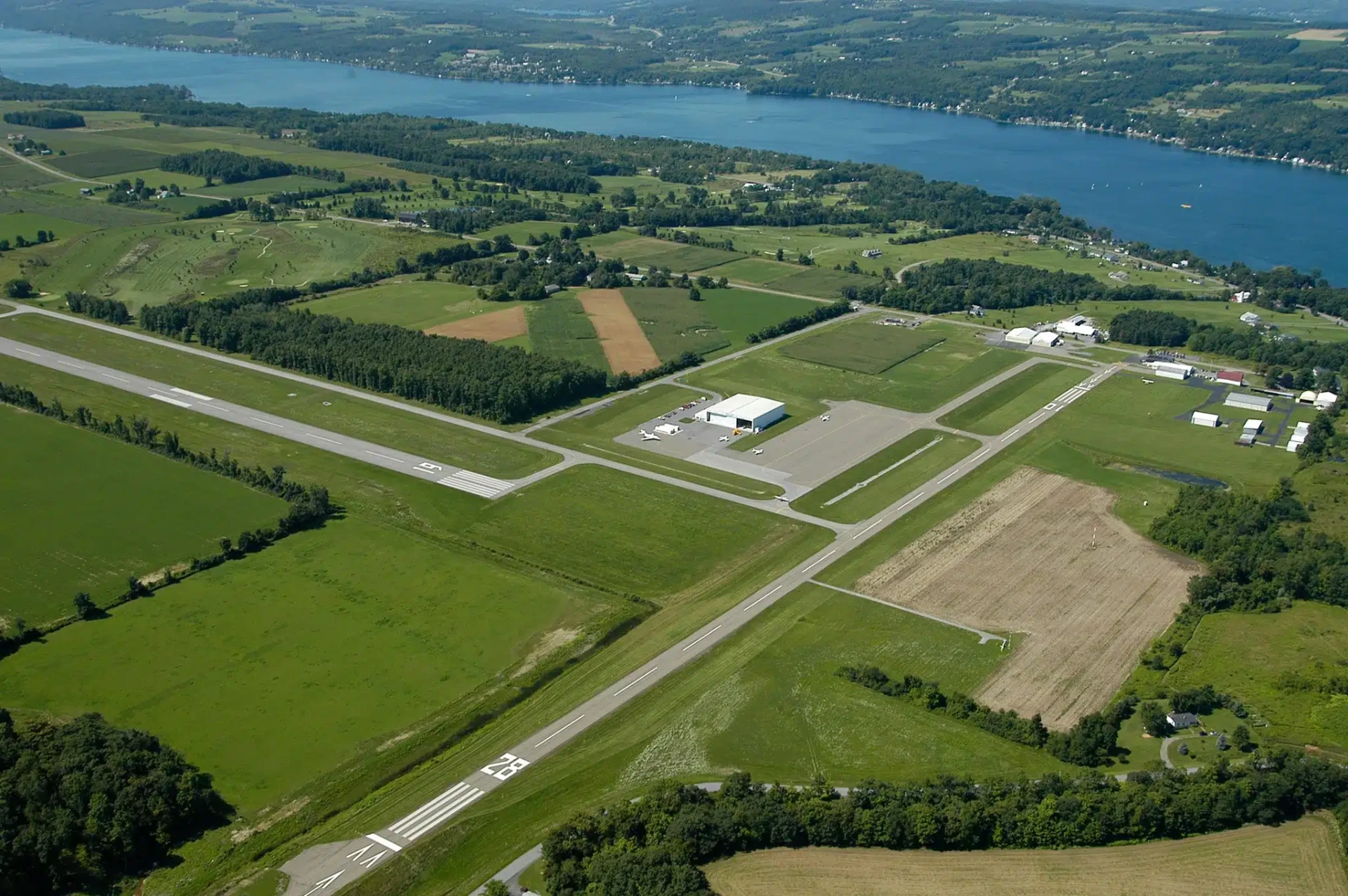 Aerial view of Penn Yan Airport (KPEO) runways and ramp with Keuka Lake in the distance